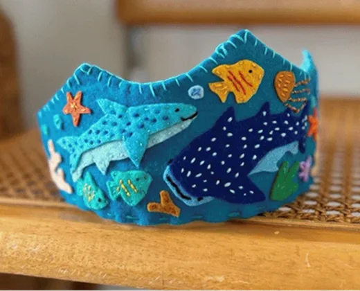 Coroa de feltro azul do tema fundo do mar, com tubarão-baleia, peixes e estrelas-do-mar aplicados e ponto festonê na borda